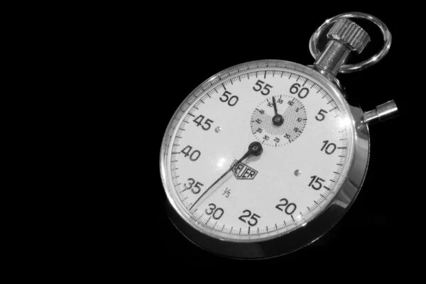 Vintage mechanical stopwatch with black dial against a dark background