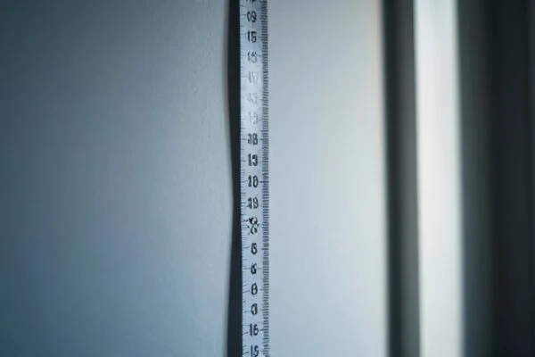A fabric tape measure hanging vertically against a plain wall beside a doorway