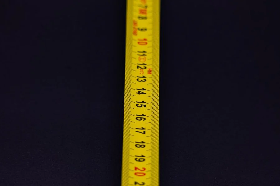 Detailed shot of a yellow measuring tape with numbers on a dark background.